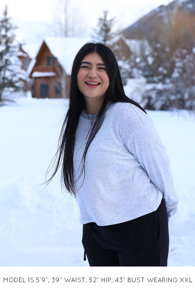 Model with snowy background wearing grey long sleeve top by Miakado. 