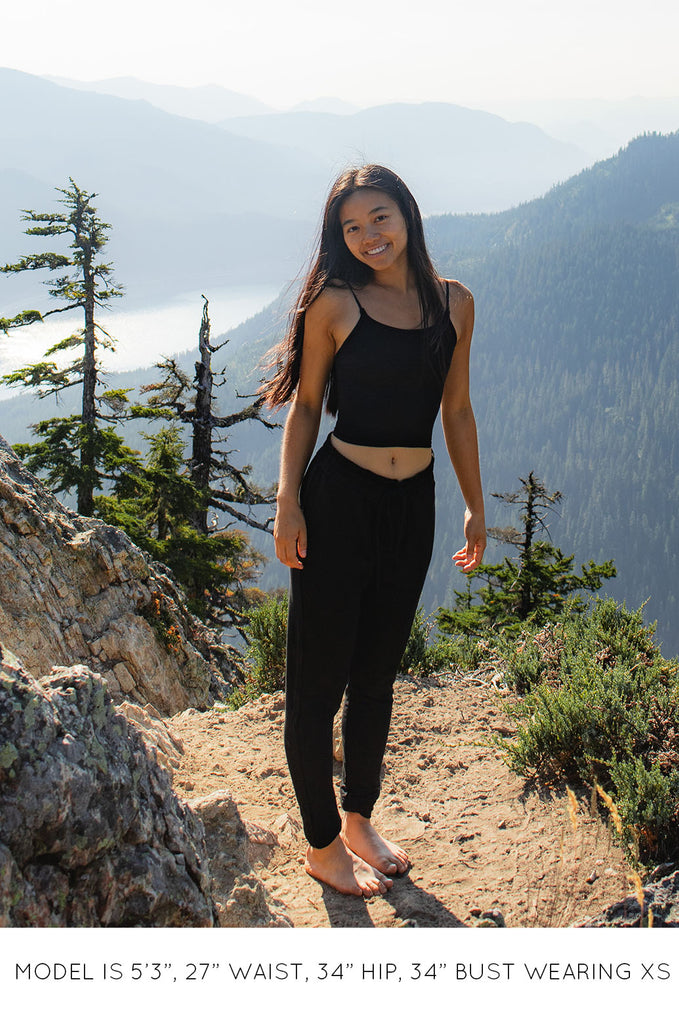 Model wearing a black Miakoda Brami crop top with black pants. 