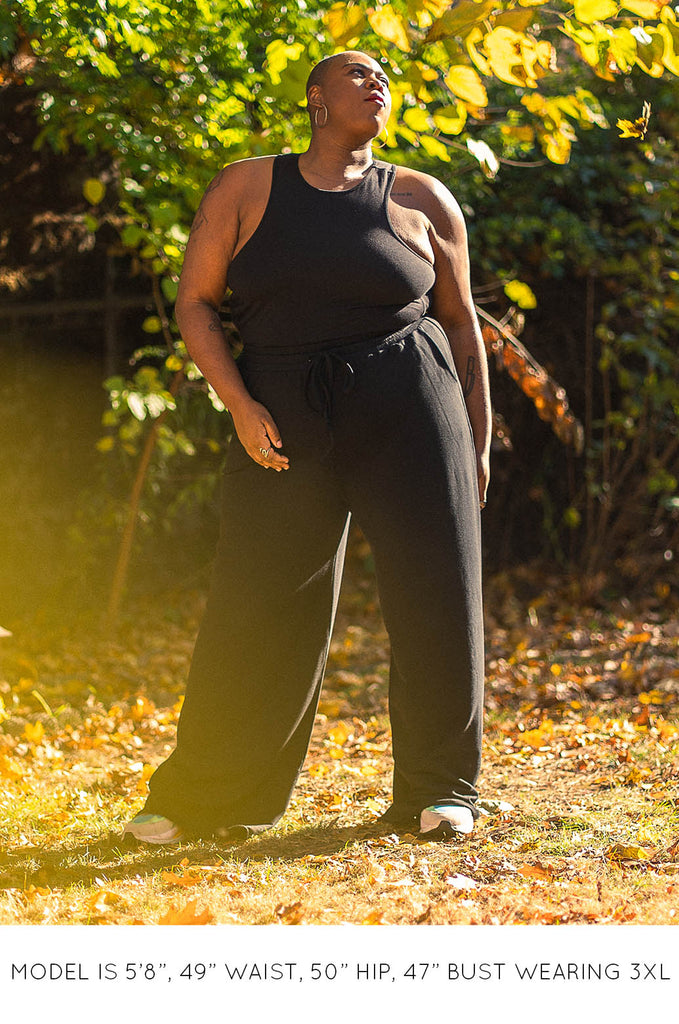 Model in front of tree wearing black racer back tank and black pants by Miakoda. 