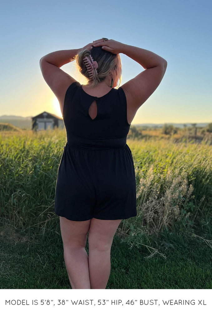 Back view of model in field wearing black Summer Romper by Miakoda. 