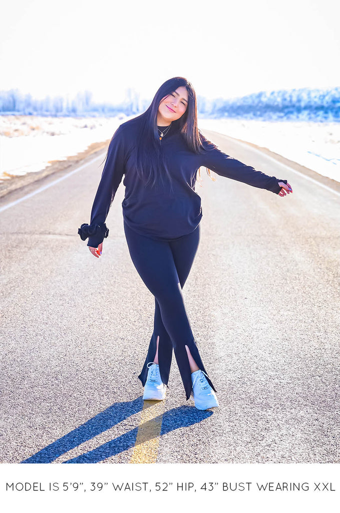 Model on road wearing black Sweater and Split Leggings by Miakoda. 