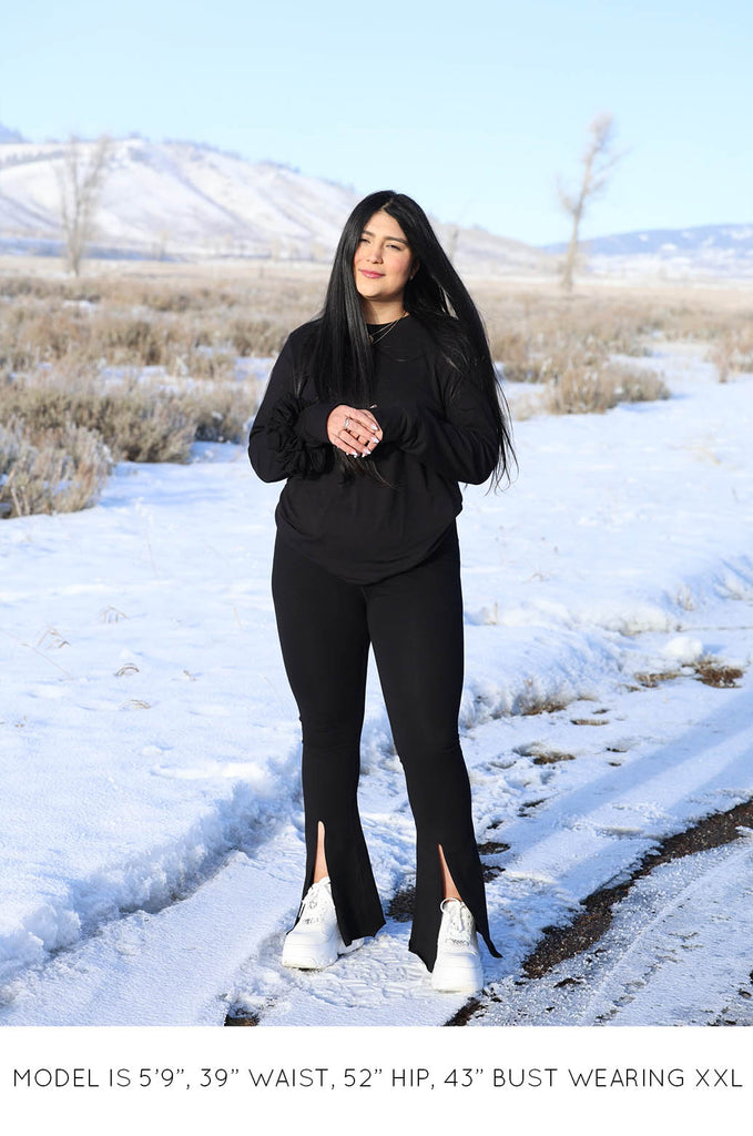 Model with snowy background wearing black Sweater and Split Leggings by Miakoda. 