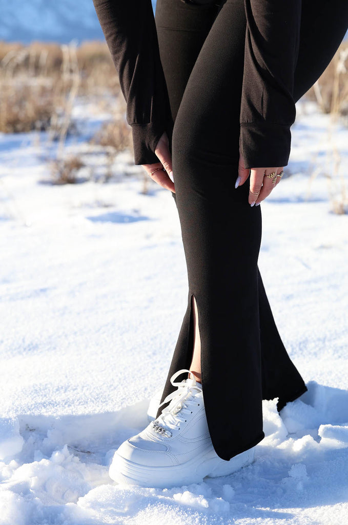 Close-up of model with snowy background wearing black Split Leggings by Miakoda. 
