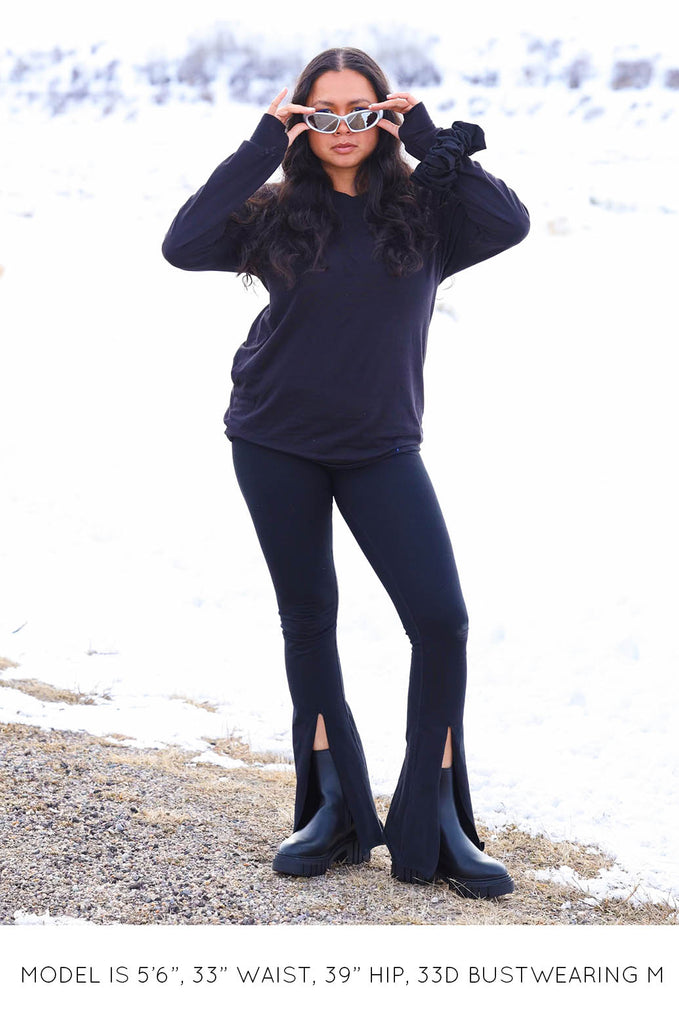 Model with snowy background wearing black Sweater and Split Leggings by Miakoda. 