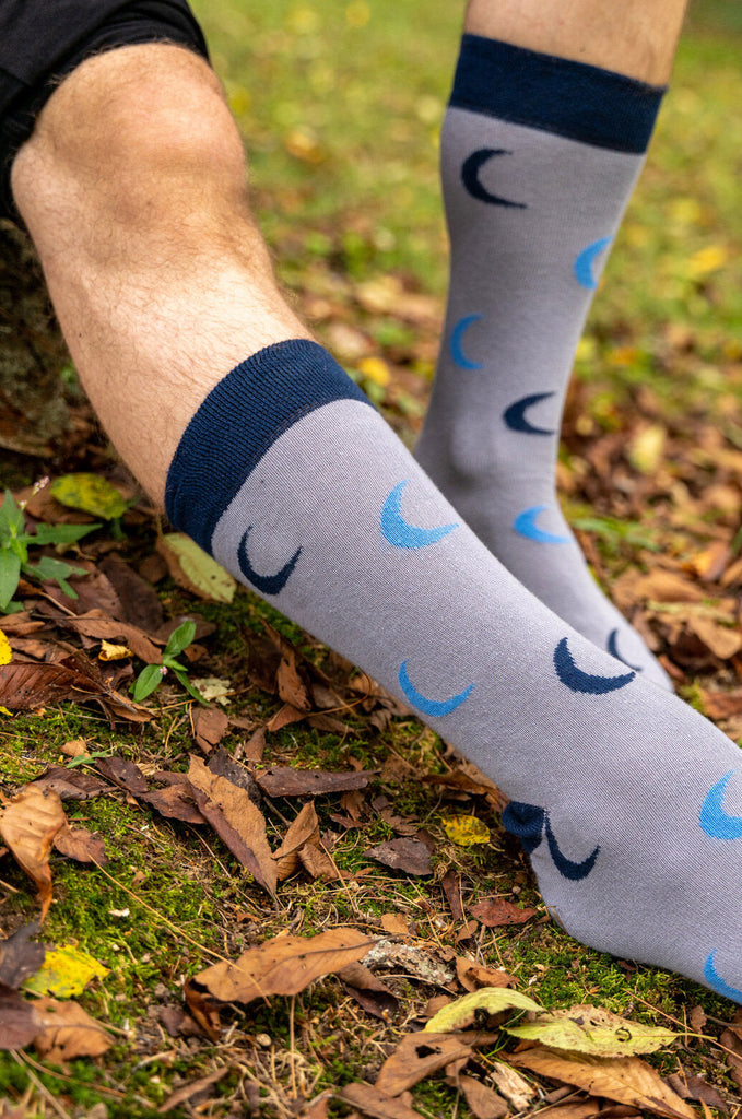 Close-up of man wearing grey and blue Miakoda unisex Moon socks. 