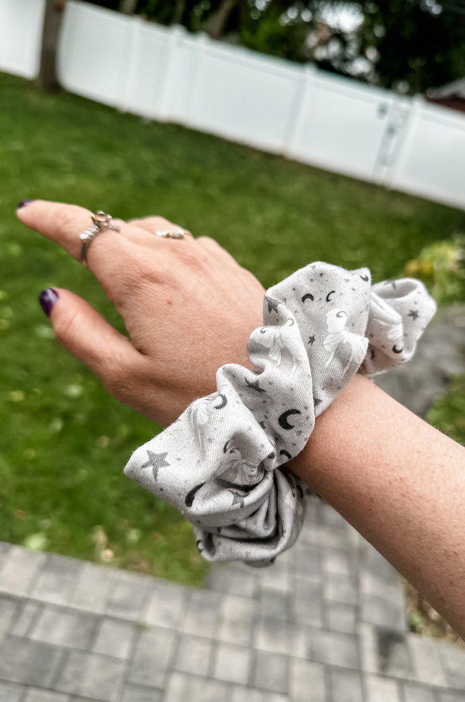 Arm with large grey print scrunchie by Miakoda. 