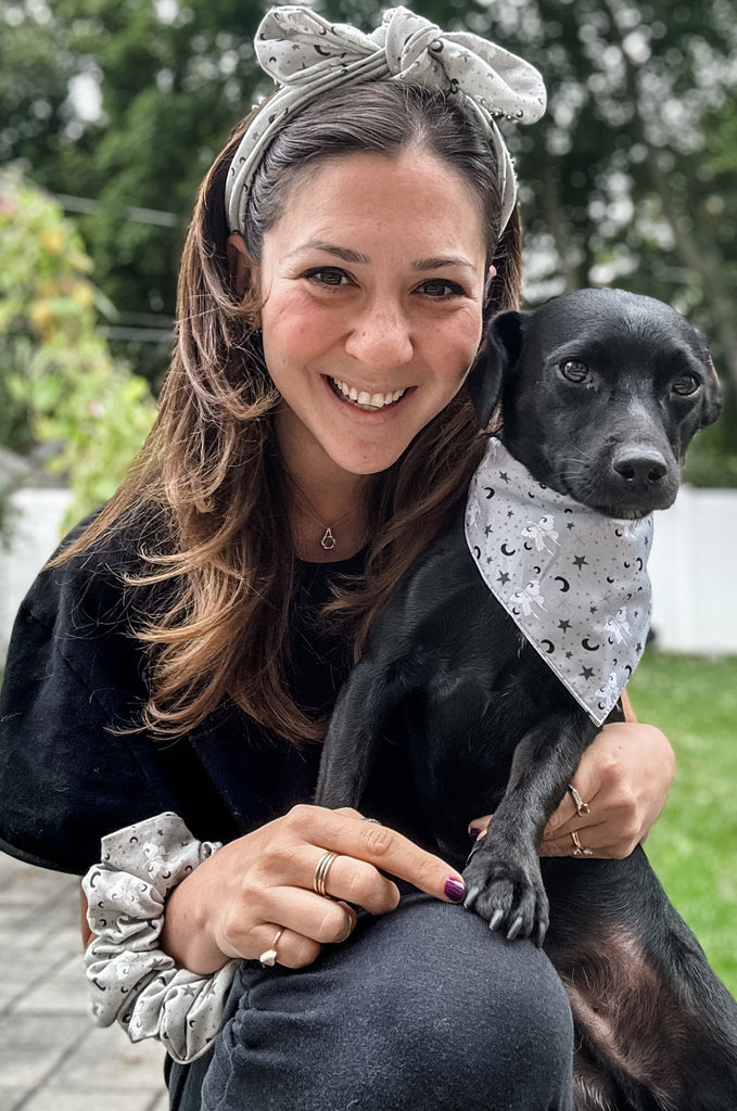 Woman wearing grey print headband with dog with matching bandana by Miakoda. 