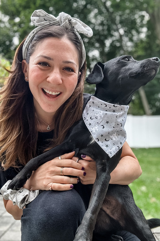 Woman wearing grey print headband with dog wearing matching bandana by Miakoda. 